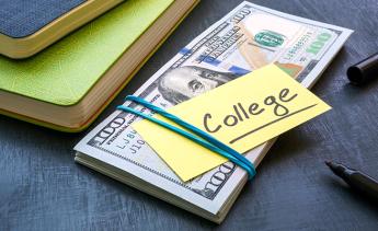 A stack of one hundred dollar bills with a yellow post-it note that reads College stuck to it next to some notebooks and pens