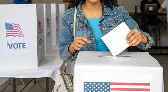 Young black woman dropping her ballot into a ballot box