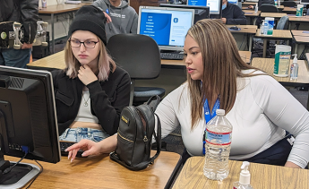 Student at a computer receiving help enrolling in classes