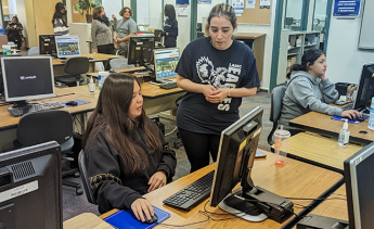 Student at a computer getting help enrolling in classes by an LAMC representative