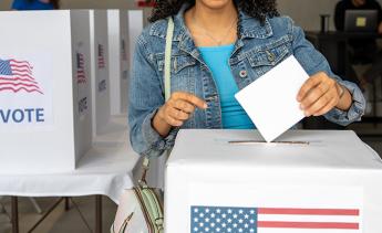 Young black woman dropping her ballot into a ballot box