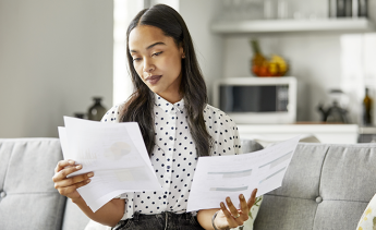 Young African-American woman looking at financial statements on her couch