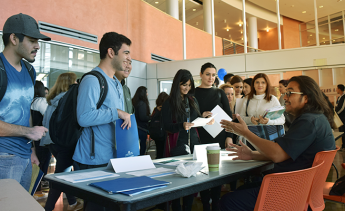 Students taking to a faculty member sitting at a table at Major Day