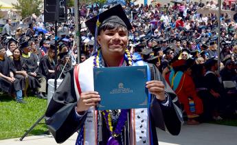 Student holding an LAMC certificate holder at graduation